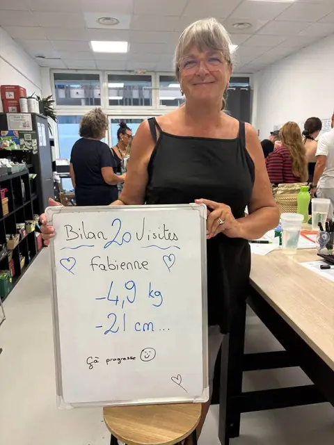 Souriante, une membre désigne les chiffres de son bilan, inscrits sur l’ardoise